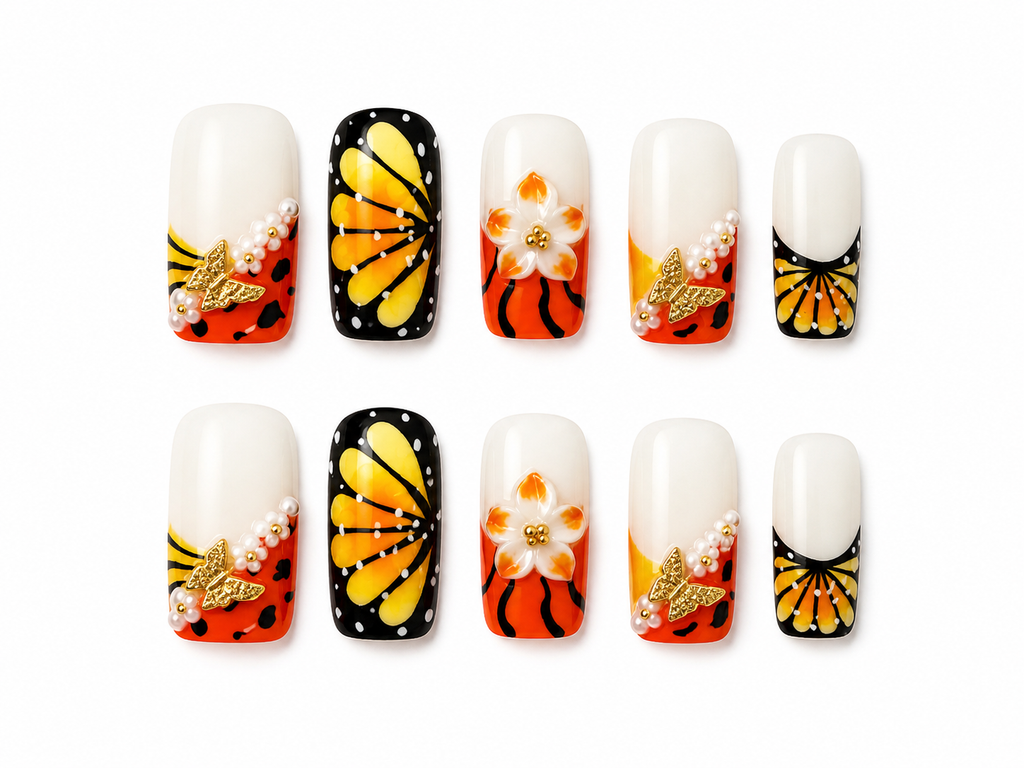monarch butterfly inspired press-on nails on a white background with gold butterfly charms, pearl accents, and a raised 3D floral centerpiece.