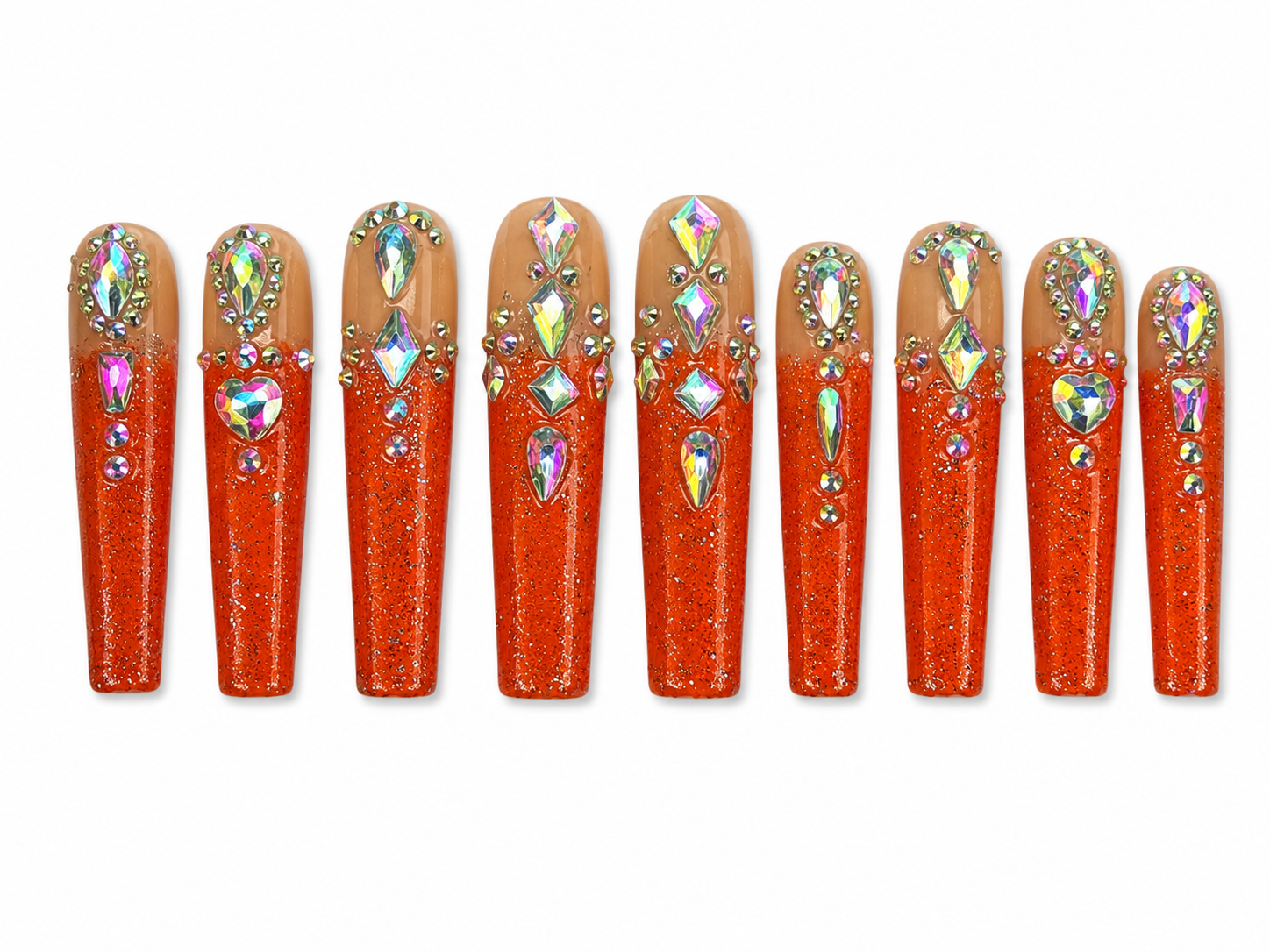 Long coffin press-on nails with nude and orange glitter ombré design, featuring holographic rhinestones and crystal embellishments on a white background.