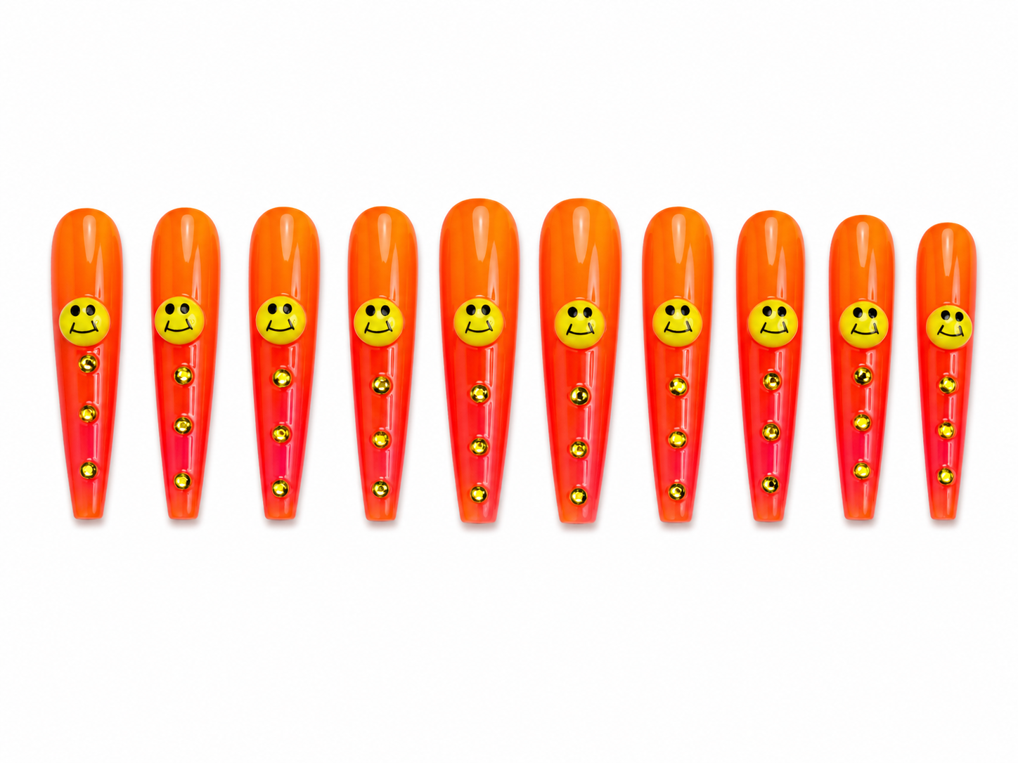 Extra-long coffin press-ons are bold orange-to-red ombre with a yellow smiley face charm on each nail and a trail of gold rhinestones cascading down the length. 