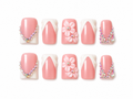 Set of pink press on nails with floral designs and decorative elements on a white background.