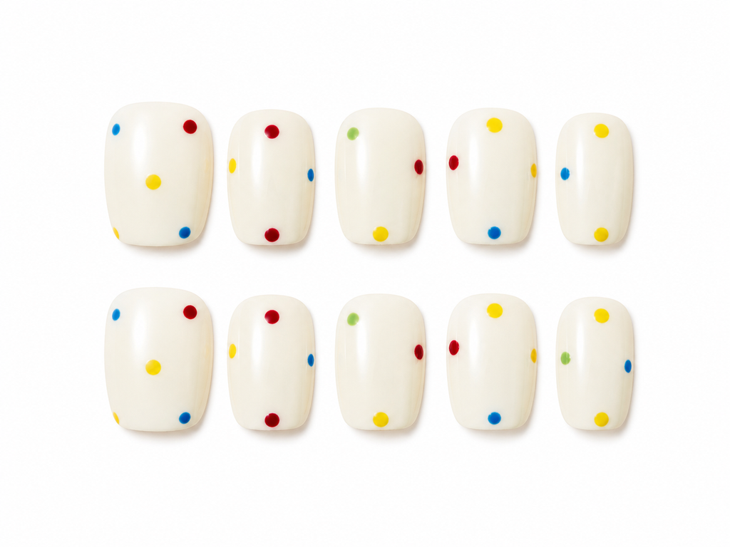 Set of short square press-ons, creamy white with a scatter of bright polka dots in red, yellow, blue, and green on a white background.