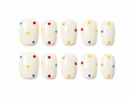 Set of short square press-ons, creamy white with a scatter of bright polka dots in red, yellow, blue, and green on a white background.